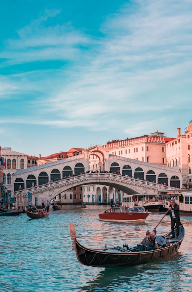 A gondola on a canal in front of a stone bridge