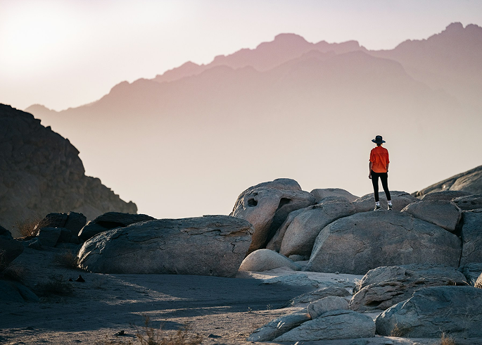 A person standing on rocks in front of mountains